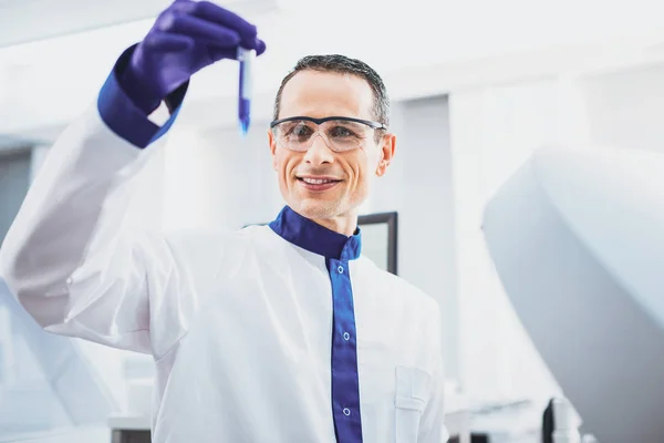 Positive delighted lab assistant checking blue liquid — Stock Photo, Image