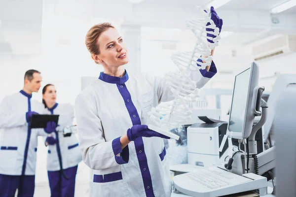 Cheerful practitioner demonstrating model of DNA