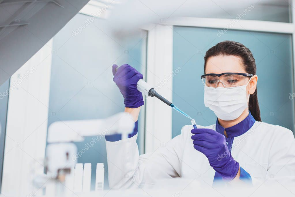 Concentrated practitioner taking specimen from test tube