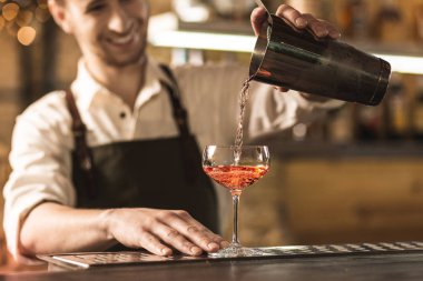 Güzel genç barmen bir kokteyl bardağına dökme