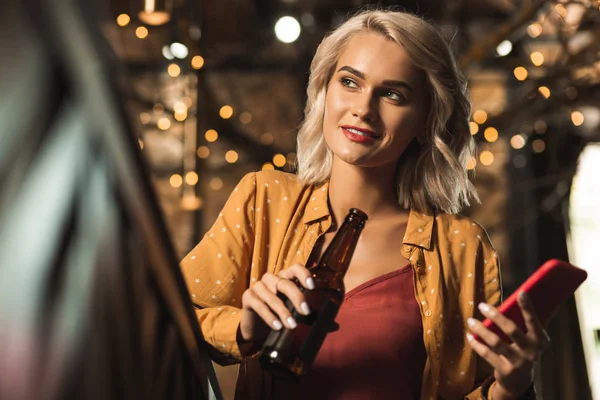 Piacevole giovane donna che beve birra e guarda il barman — Foto Stock