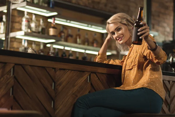 Glada blond kvinna att höja hennes ölflaska — Stockfoto