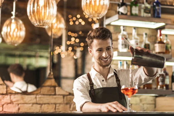 Joven barman alegre llenando el vaso con cóctel — Foto de Stock