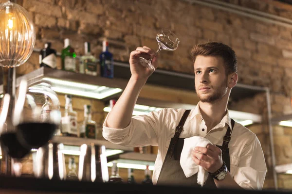 Young professional barman checking cleanness of glass — Stock Photo, Image