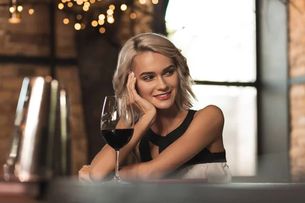 Mujer rubia bonita sentada en el bar y sonriendo a alguien —  Fotos de Stock