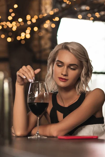 Beautiful blonde woman contemplating her glass of wine