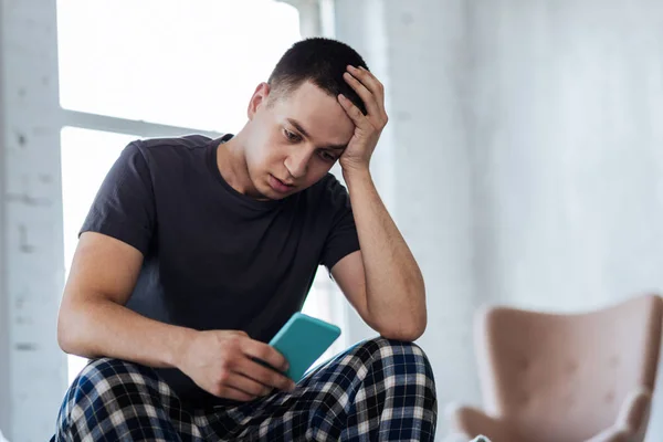 Trauriger Mann schaut auf sein Handy — Stockfoto