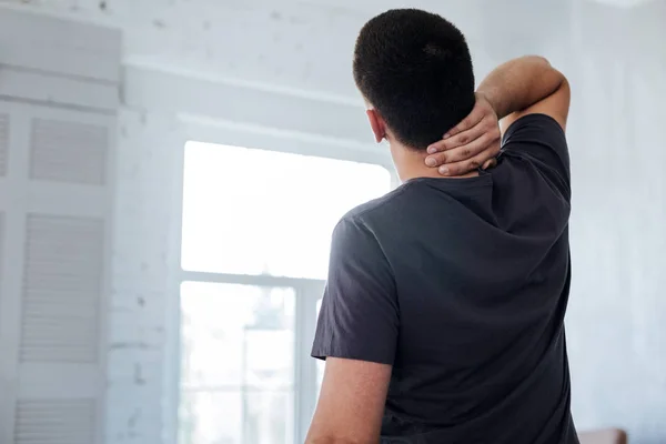 Hombre de pelo oscuro sosteniendo su cuello —  Fotos de Stock