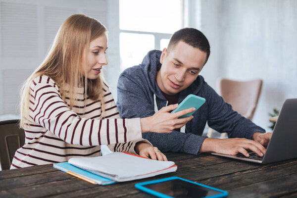 Веселая девушка показывает фотографии своему парню
