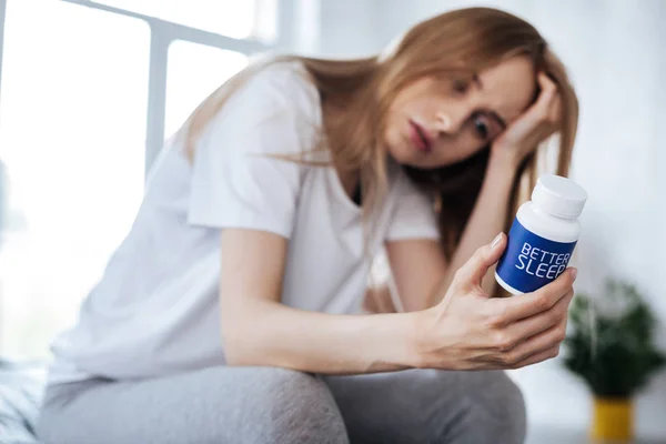 Mujer preocupada mirando sus pastillas para dormir —  Fotos de Stock