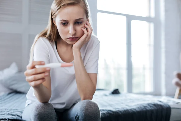 Mujer infeliz sosteniendo su prueba de embarazo —  Fotos de Stock