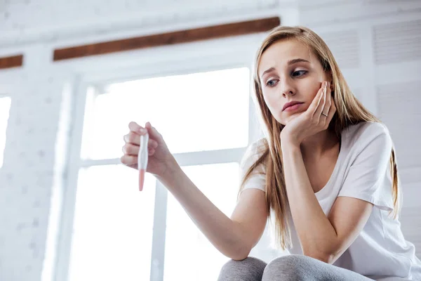 Concerned woman holding her pregnancy test — Stock Photo, Image