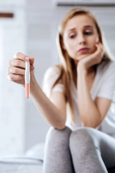 Low-spirited woman holding her pregnancy test — Stock Photo, Image