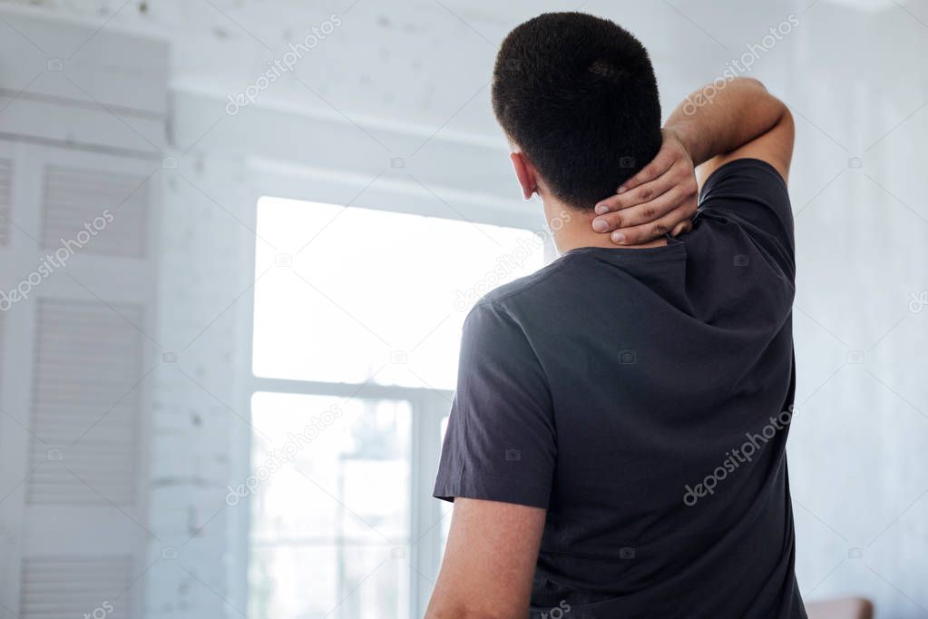 Dark-haired man holding his neck