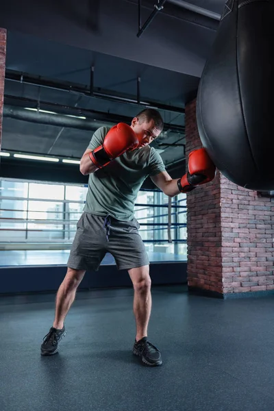 Mörkhårig man klädd i röd boxningshandskar träning i gym — Stockfoto
