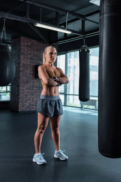 Blonda boxare stående i gym nära slagsäckar — Stockfoto