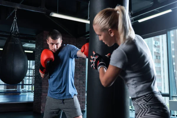 Blonde-haired trainer wearing leggings working with young boxer — Stock Photo, Image
