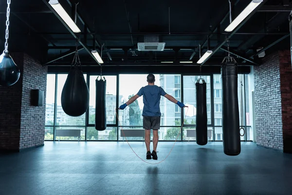 Atletisk man hoppa rep i gym med slagsäckar på boxare — Stockfoto