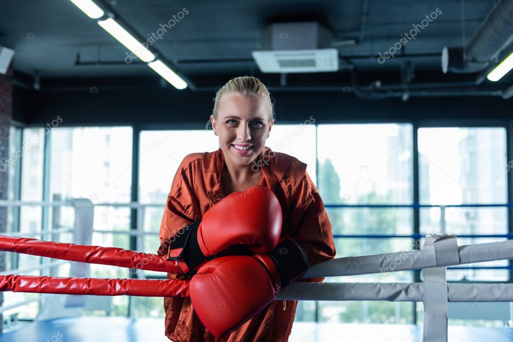 Smiling blue-eyed woman boxing in ring while training hard