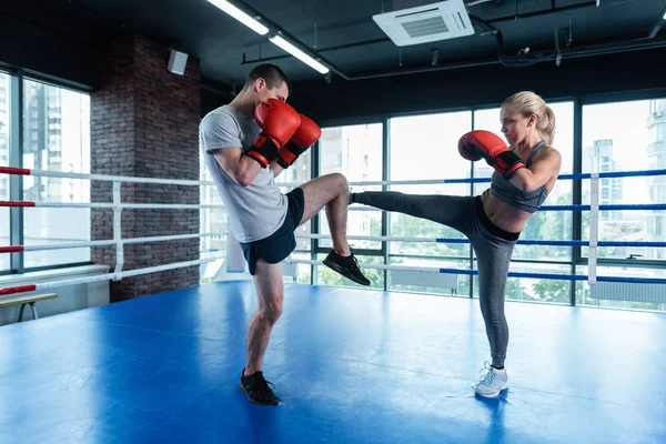 Dark-haired man working out on boxing ring with wife — Stock Photo, Image