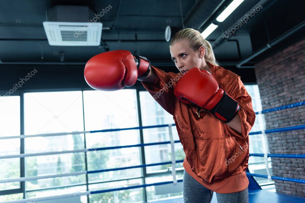 Blonde-haired woman enjoying sport activity while boxing