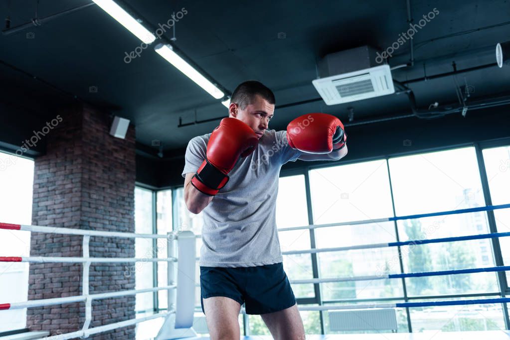 Active man. Strong active athletic man feeling extremely happy while enjoying boxing in gym
