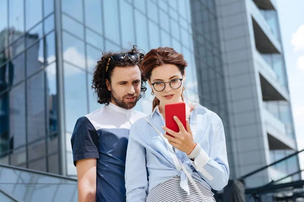 Joven freelancer sosteniendo el teléfono rojo en sus manos —  Fotos de Stock