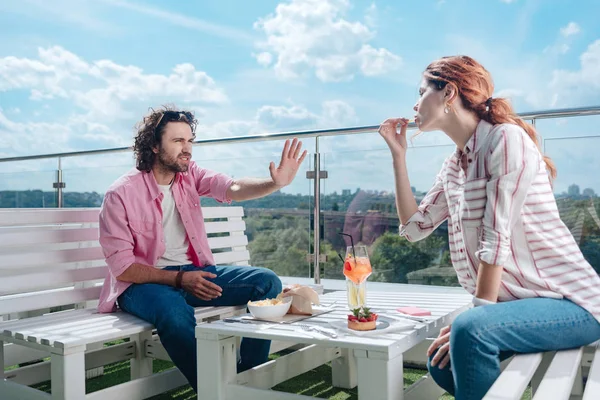 Curly man not liking manners of his girlfriend