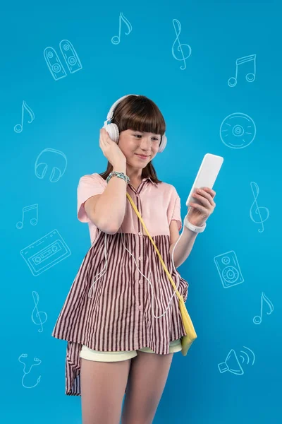 Menina bonita tocando seus fones de ouvido e ouvir música — Fotografia de Stock