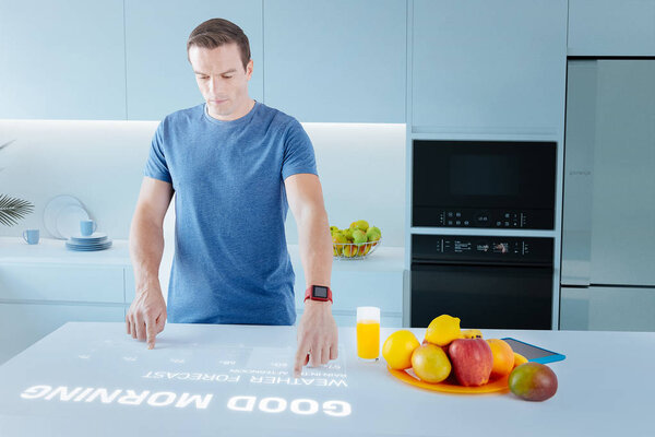 Busy man planning his day while touching the hologram on in the kitchen