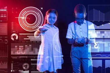 Sevimli kız bir uzaktan kumanda ve bir çocuk bir smartphone ile ayakta tutan