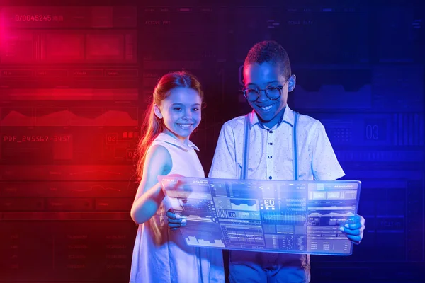 Mutlu çocuklar şeffaf bir gadget tutarken gülümseyen