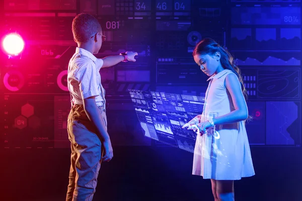Chica cuidadosa tocando el anuncio del holograma su amigo ayudándola con su proyecto — Foto de Stock