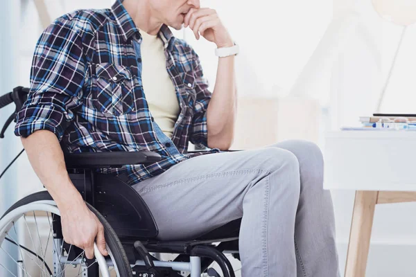 Thoughtful invalid man sitting in semi position