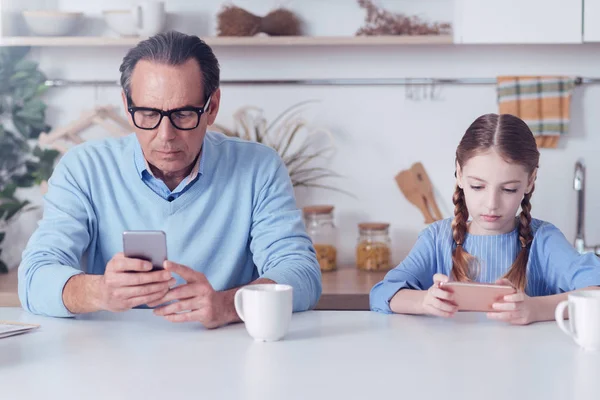 Serious buen aspecto padre e hija usando sus teléfonos inteligentes — Foto de Stock