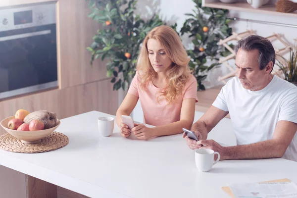 Niza hombre y mujer serios usando sus teléfonos inteligentes —  Fotos de Stock