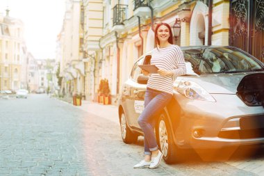 Arabanın yakınında güzel bir sokakta duran gülümseyen kadın