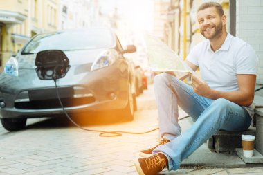 Bir harita ile oturma ve gülümseyerek mutlu bir adam