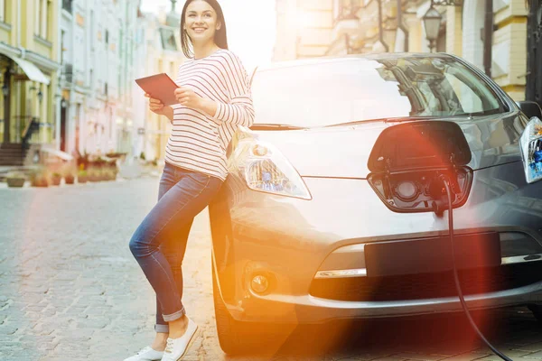 Mulher alegre com um tablet apoiado em seu carro — Fotografia de Stock