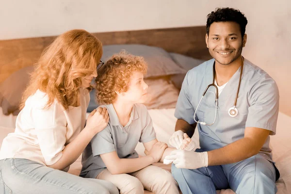 Uśmiechający się międzynarodowe lekarz trzymając rękę pacjenta — Zdjęcie stockowe