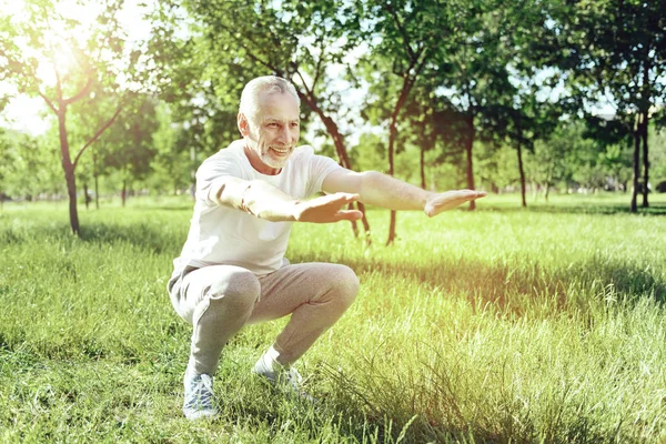 Smiling active aged man bending his knees — Stock Photo, Image