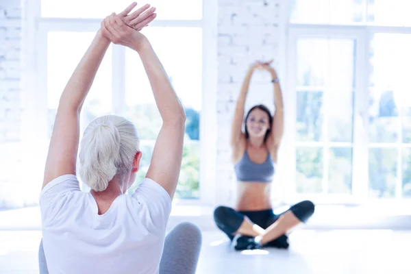 Vista posterior de la mujer anciana que estira los brazos — Foto de Stock