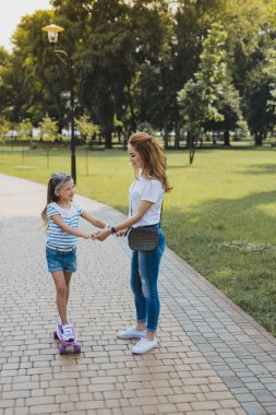 Sarışın Anne kızı kaykay üzerinde duran öğretim