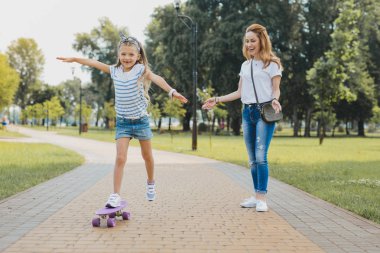 Kaykay sürme beyaz kol saati giyen küçük şirin kız
