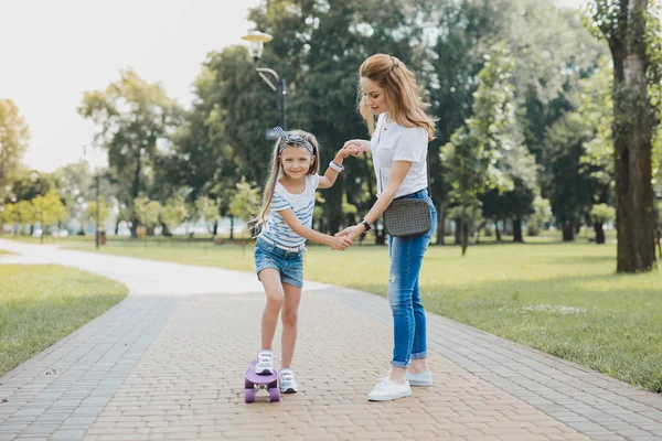 Pleasant stylish preschool girl having active walk with her mother — Stock Photo, Image