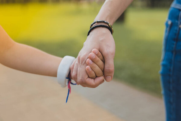 Loving modern mother wearing black bracelet holding her daughter