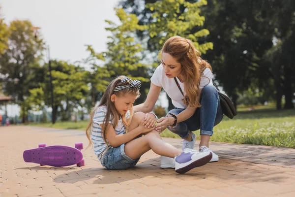 Zorgzame moeder haar actieve dochter knuffelen na een val — Stockfoto