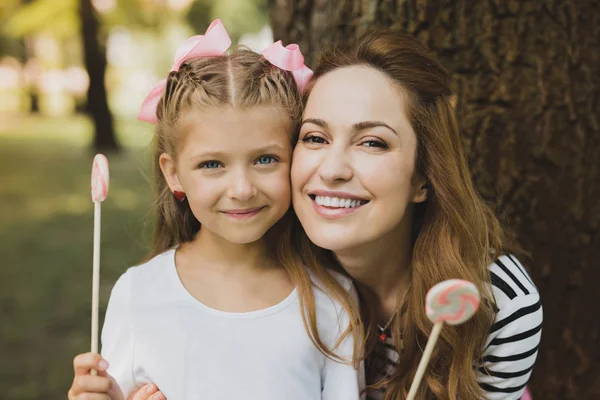 Feliz madre e hija comiendo piruletas dulces en vacaciones —  Fotos de Stock