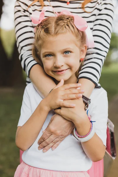Sorridente ragazza dagli occhi azzurri in piedi vicino al suo genitore premuroso — Foto Stock