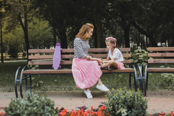 Divatos anya ül a padon a parkban, közel a lánya — Stock Fotó